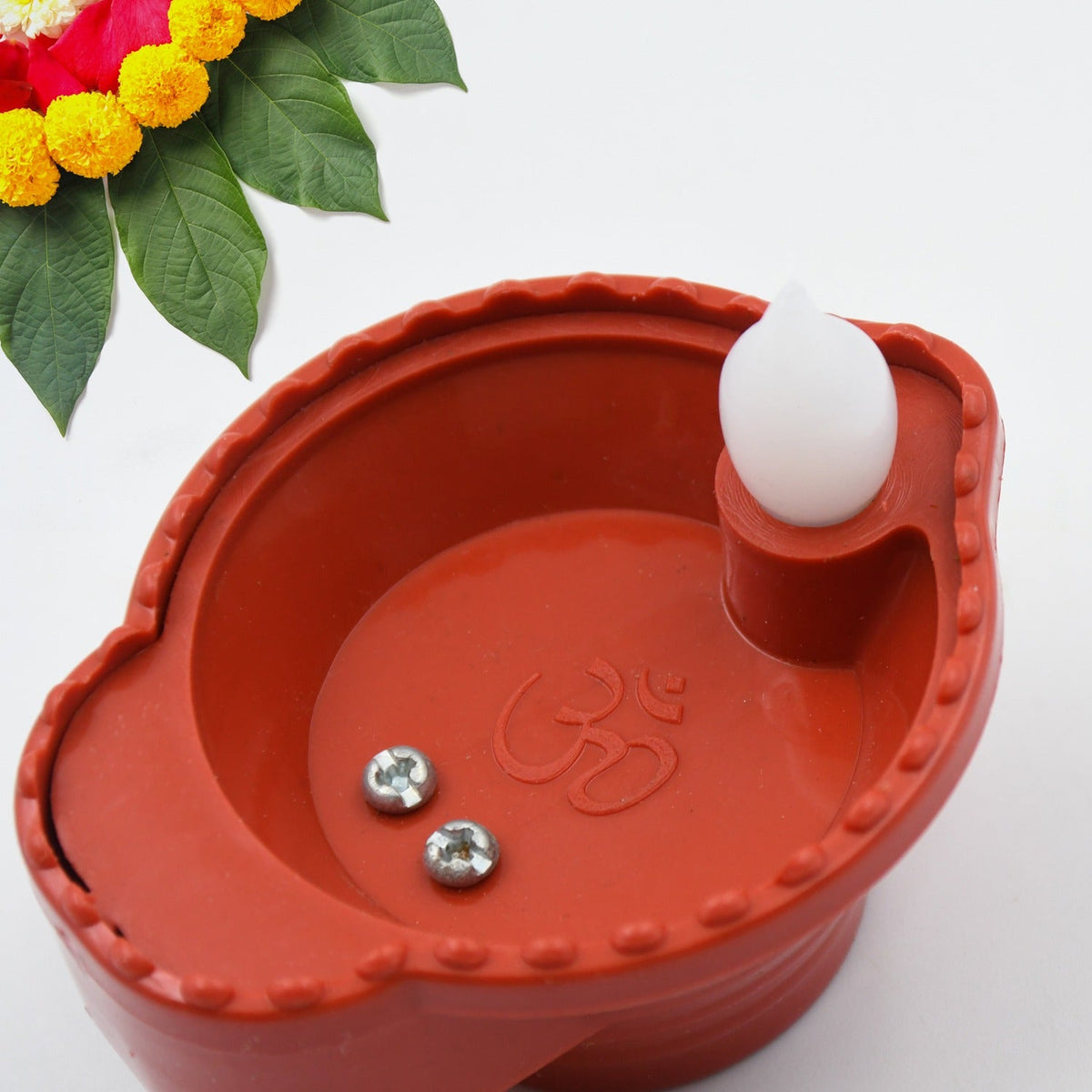Hand pouring water into a flameless diya, activating its warm LED light.